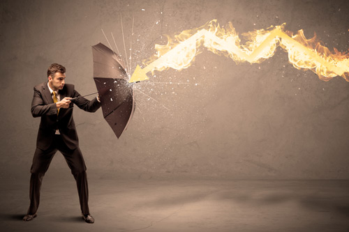 Young man in suit holds up umbrella to combat flaming arrow. managing corporate firestorms
